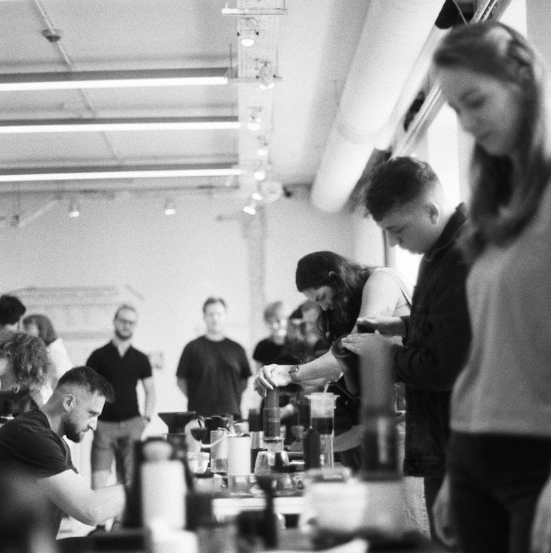 People gathered around tables with coffee brewing equipment